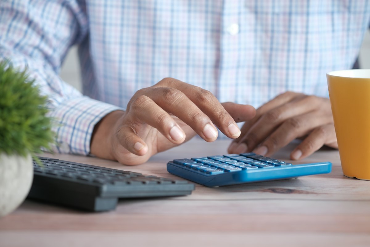 Using a calculator at a desk with a coffee mug