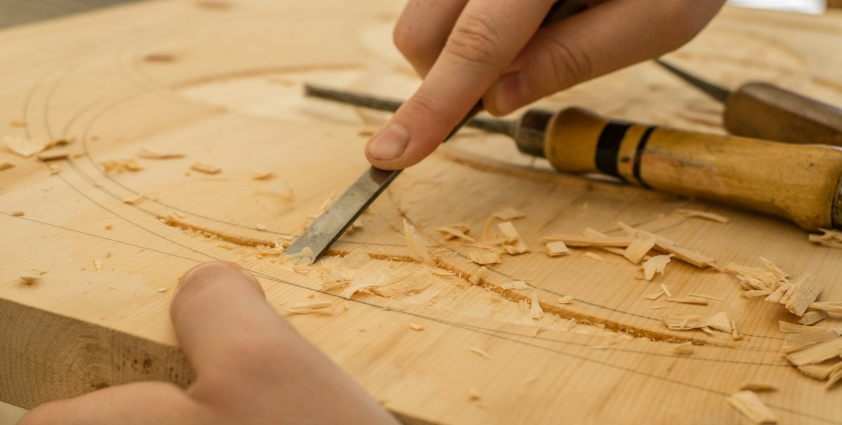 Hands carving timber with a chisel