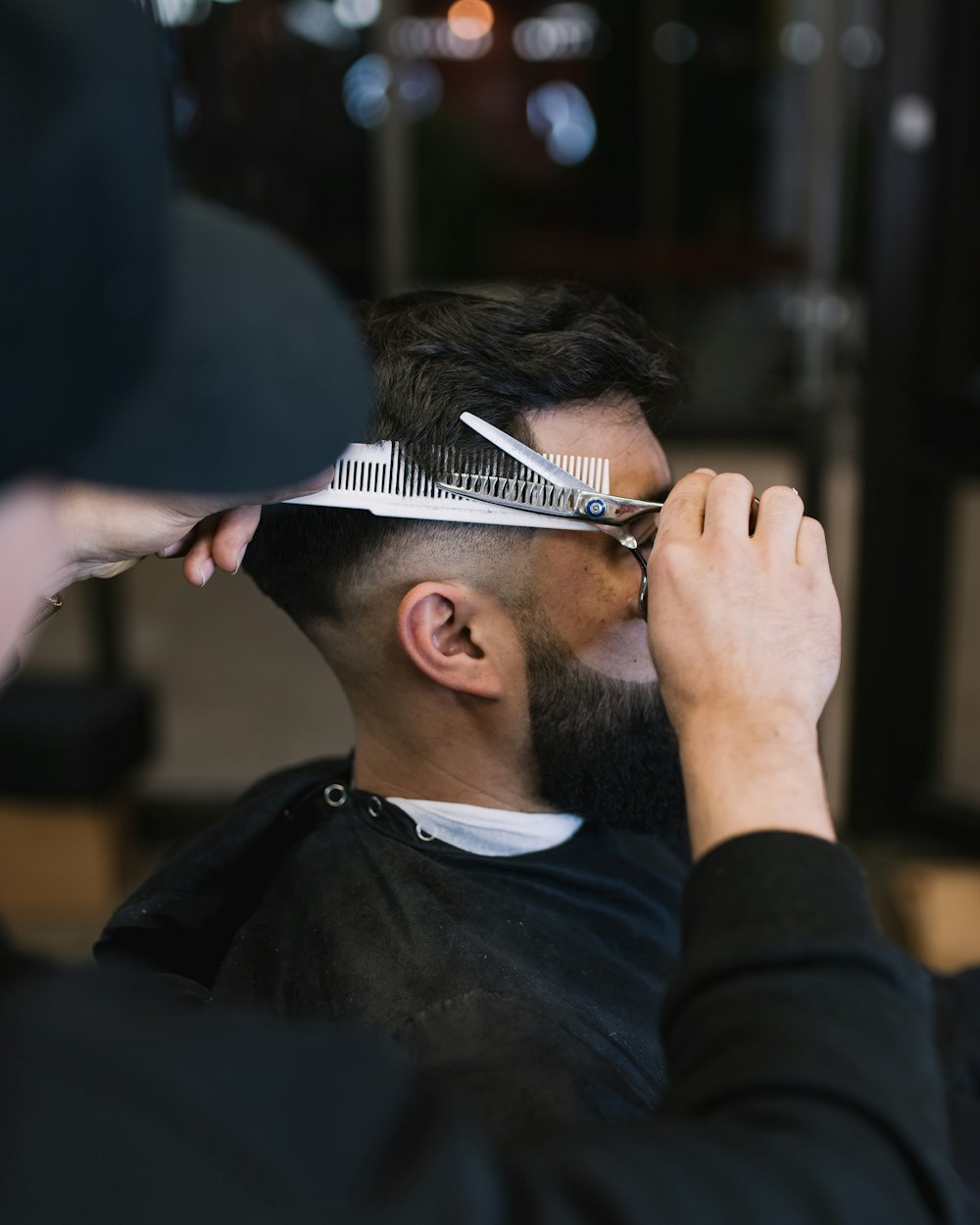 Stylist cutting a client's hair with scissors and comb