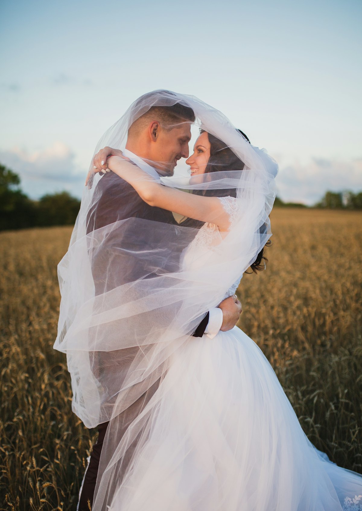 Smiling newlywed couple in a green field